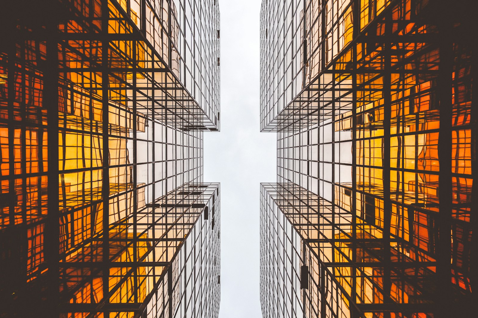 Glass high-rise towers at dusk with golden sun reflecting through striking geometry